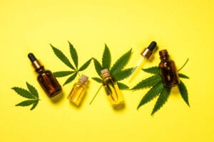 three cannabis tincture bottles and cannabis leaves on a yellow background